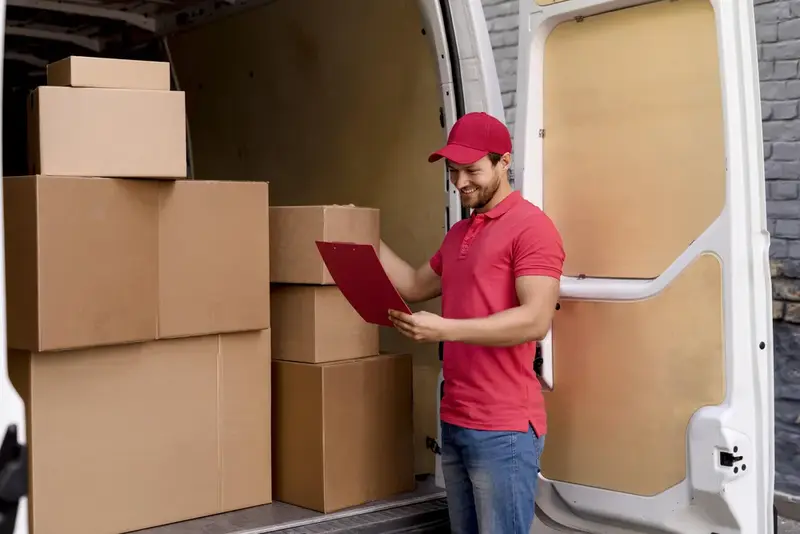 A removalist checking a list beside boxes stacked in a van