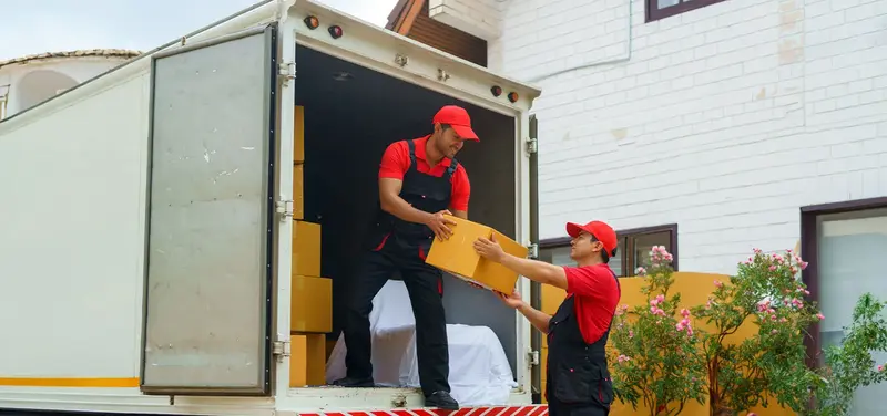 Two removalists unloading boxes from the back of a moving truck