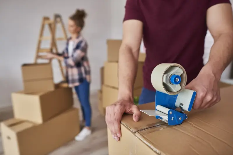 A packer sealing a moving box with tape