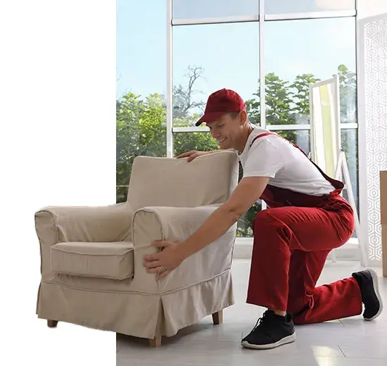 A removalist kneeling to lift a heavy armchair